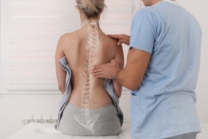 A woman with scoliosis being treated by a doctor. The male doctor is checking her back. 