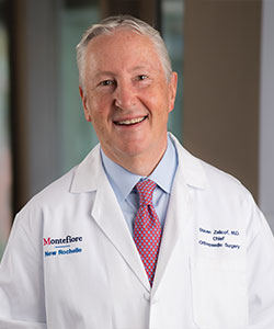 headshot of older male doctor smiling widely in white coat