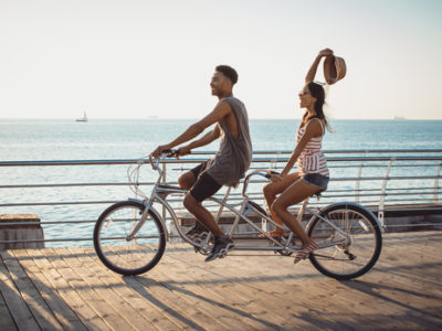 couple riding on tandem bicycle outdoors near the sea